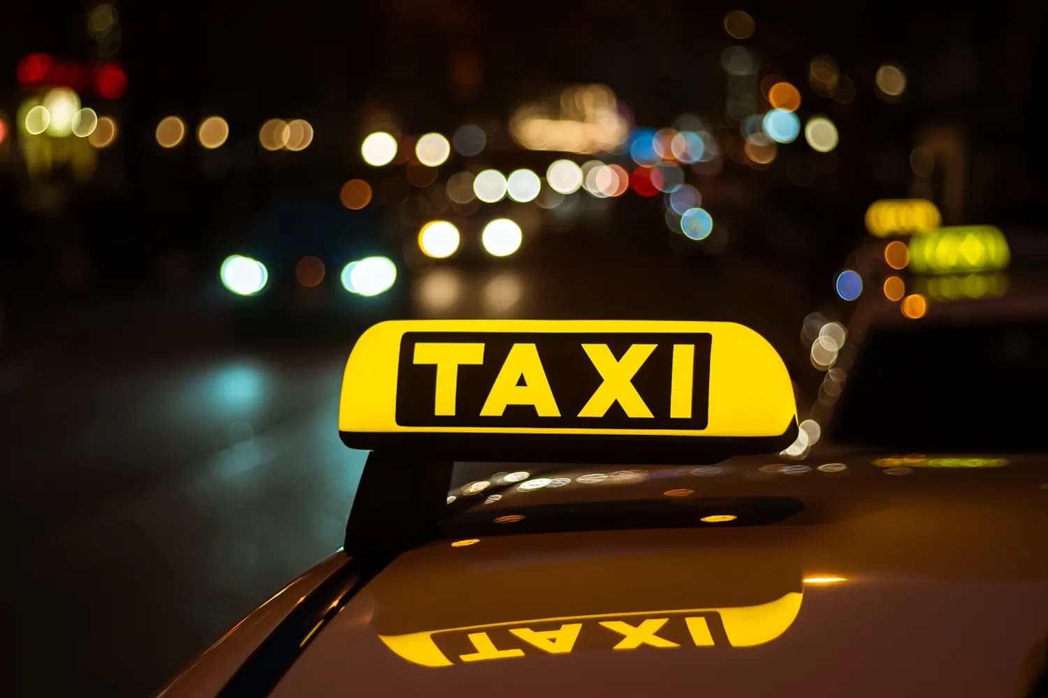 Taxi rooftop sign with night city lights