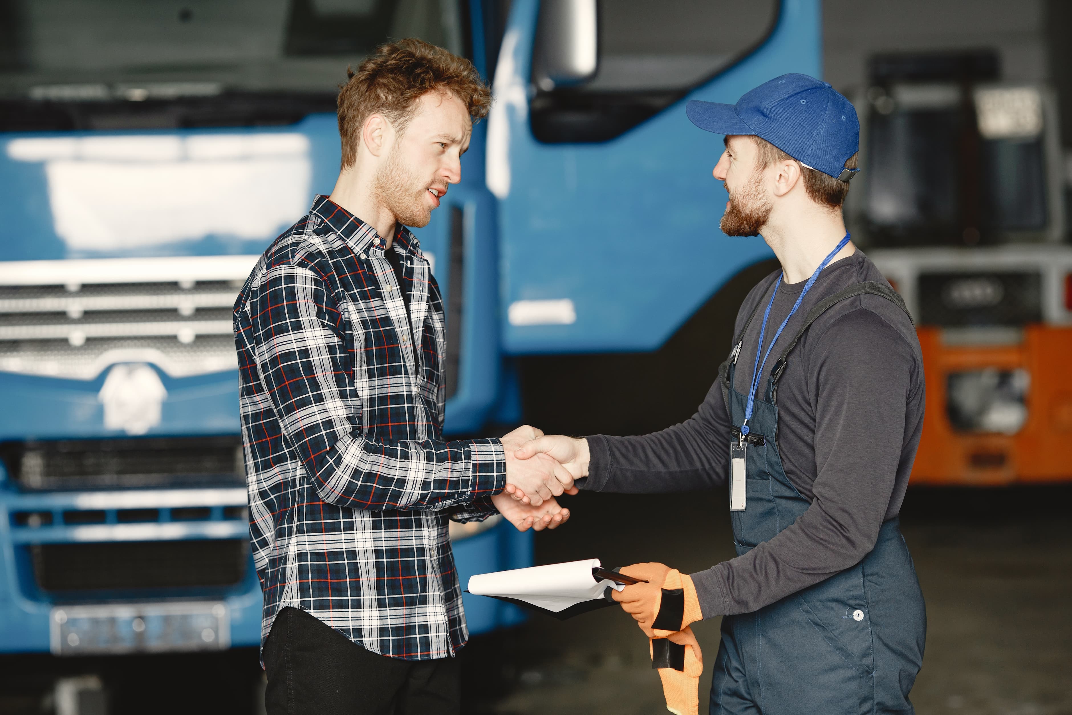Two men shaking hands beside a truck while discussing fleet management.