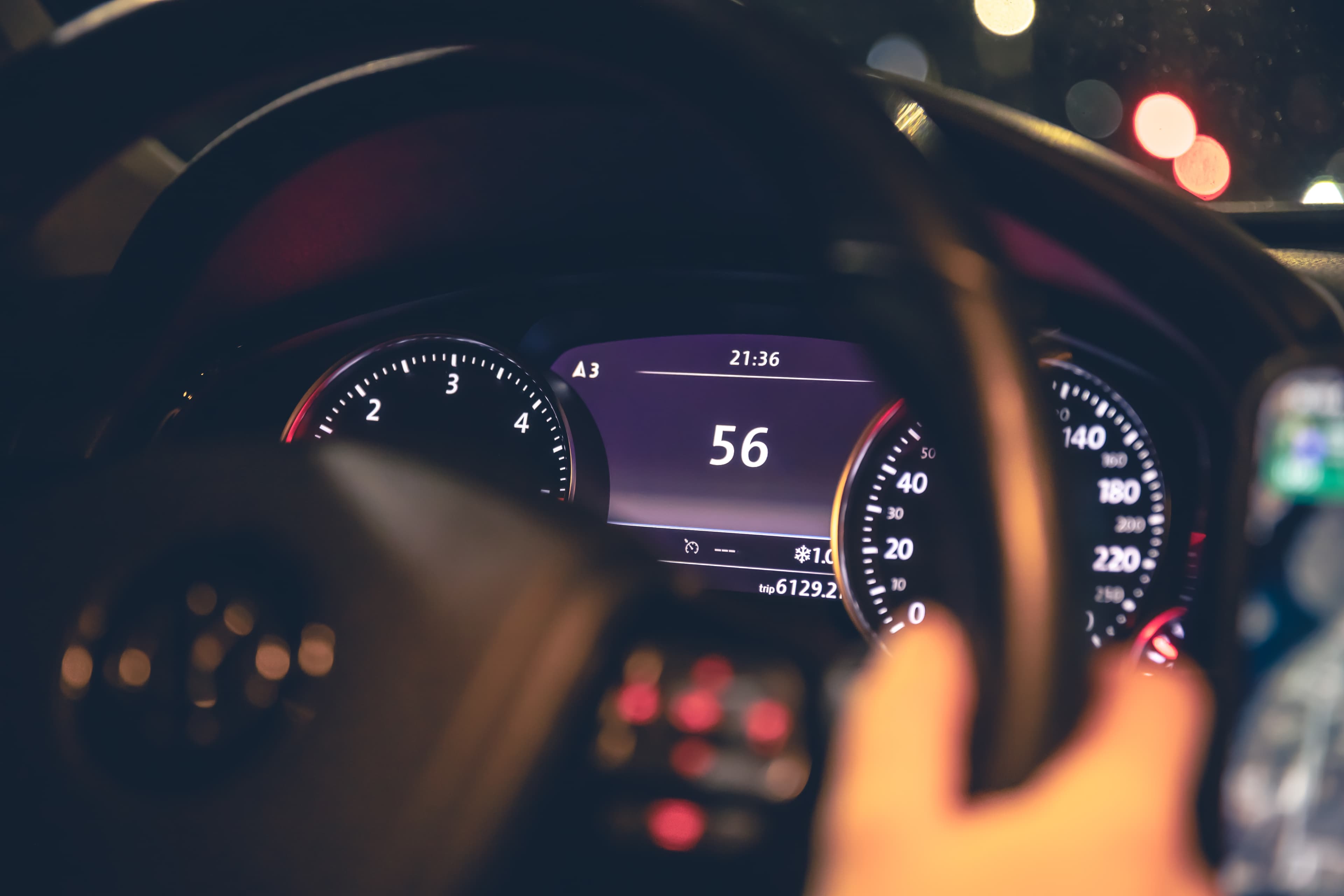 Driver behind the wheel with an illuminated vehicle dashboard.